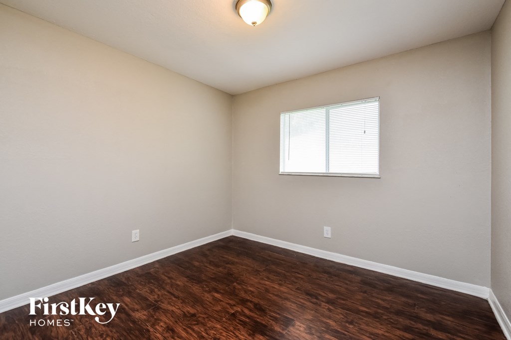 the spacious living room with wood flooring and a window