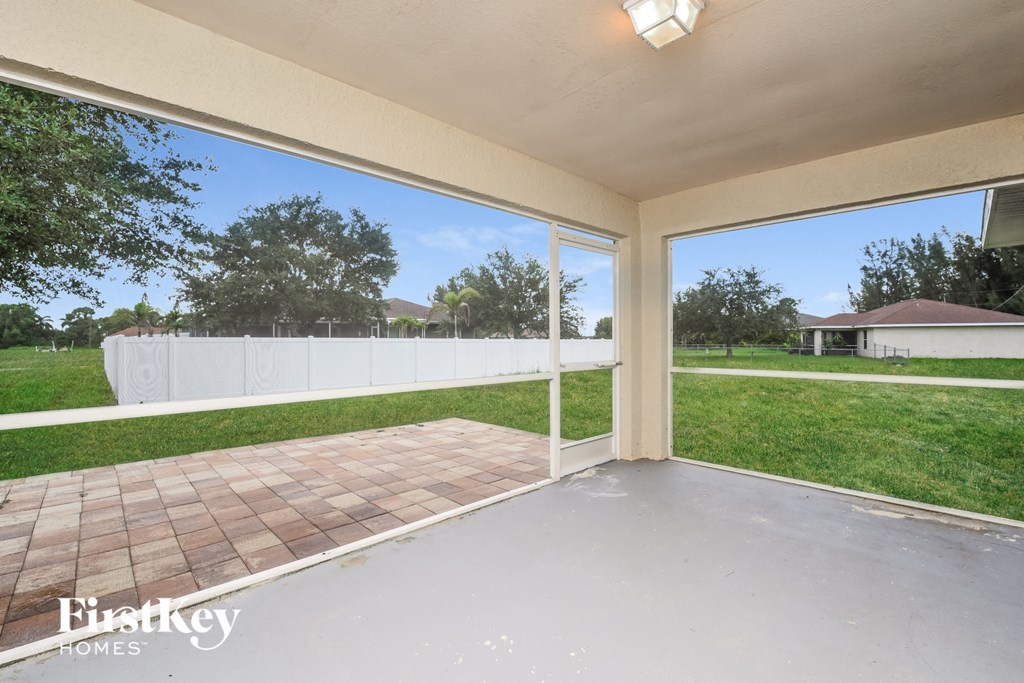a covered porch with a lawn and a white fence