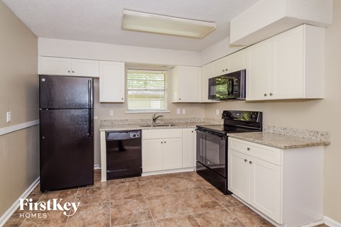 a kitchen with white cabinets and a black refrigerator