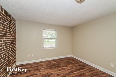 a living room with wood flooring and a brick wall and a window