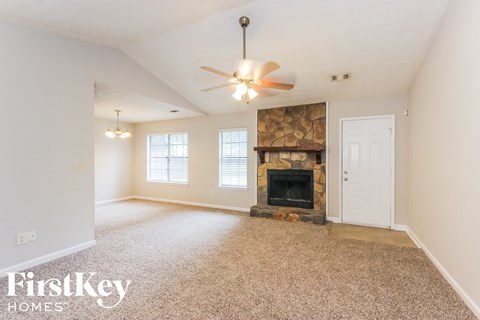 A spacious living room with a fireplace and a ceiling fan.