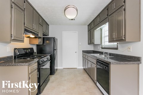 A kitchen with a black refrigerator and stove top oven.