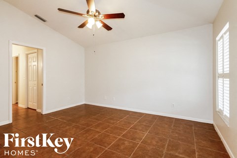 a living room with white walls and a ceiling fan