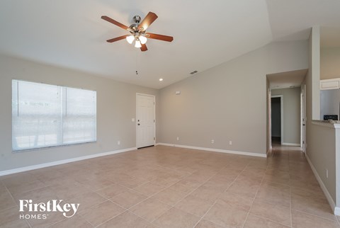 an empty living room with a ceiling fan and a large window
