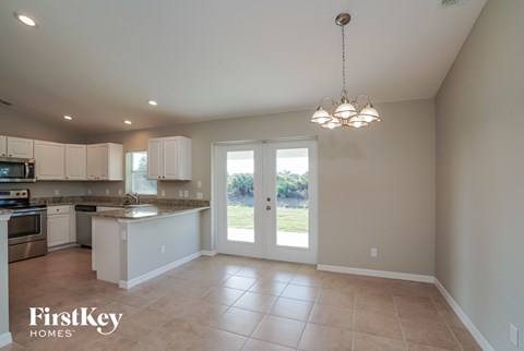an empty kitchen with white cabinets and a door to a yard