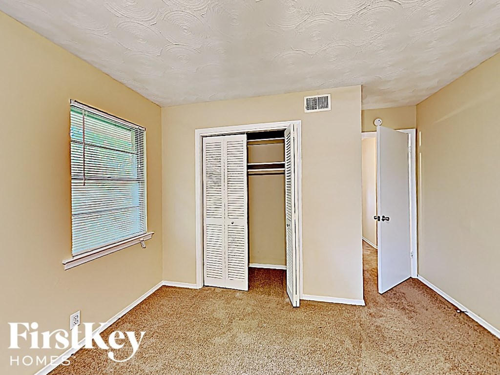 an empty bedroom with a closet and a door to the bathroom