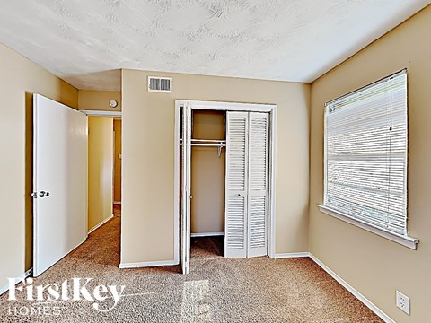 the entrance to a bedroom with a closet and a window with blinds