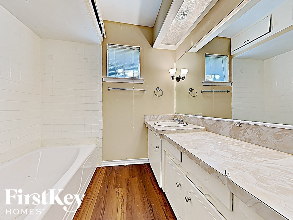 a bathroom with a tub and a sink and a mirror
