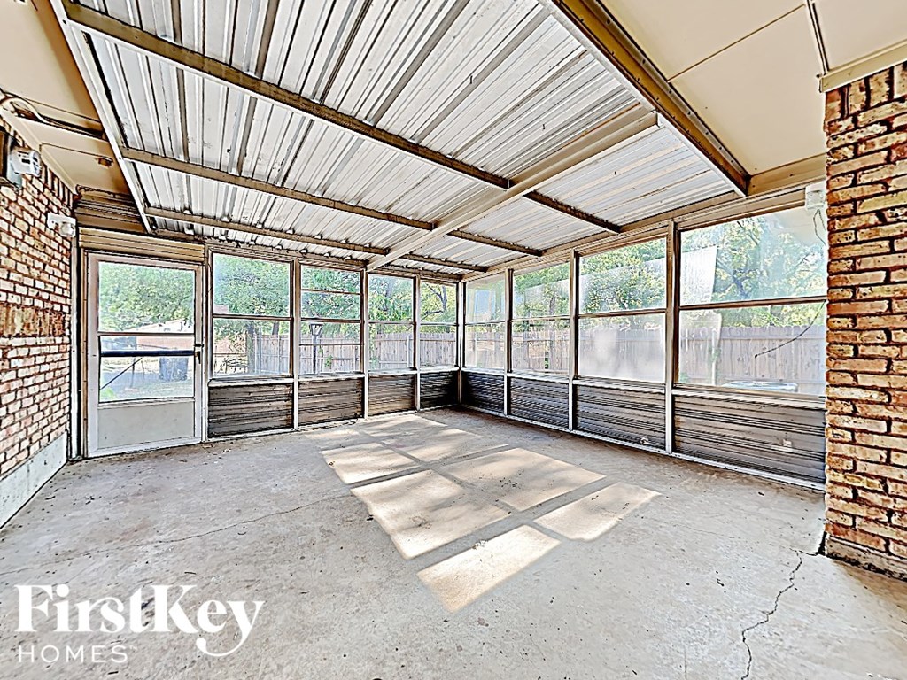 an empty living room with large windows and brick walls