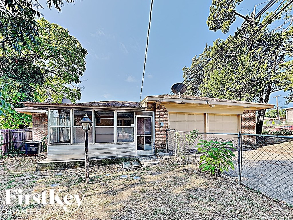 a small brick house with a chain link fence