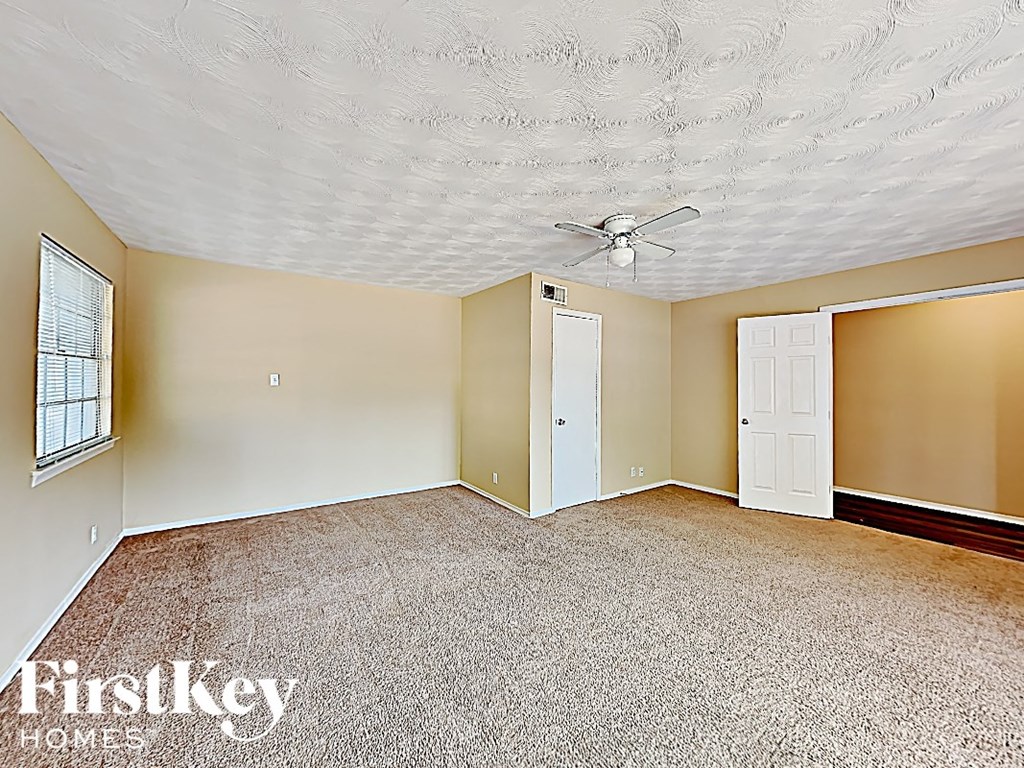an empty living room with a ceiling fan and a white door