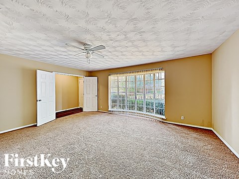 an empty living room with a ceiling fan and a window
