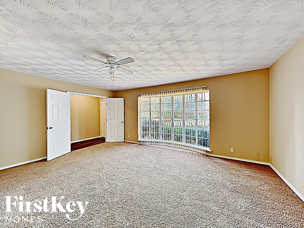 an empty living room with a ceiling fan and a window