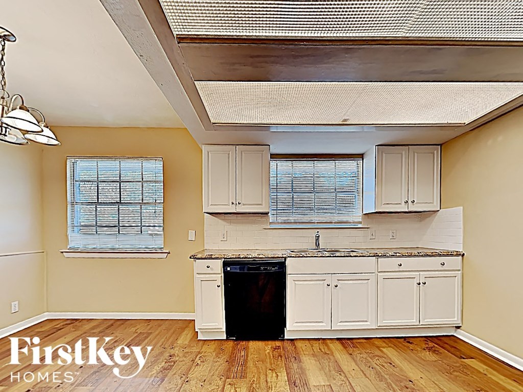 an empty kitchen with white cabinets and a black dishwasher