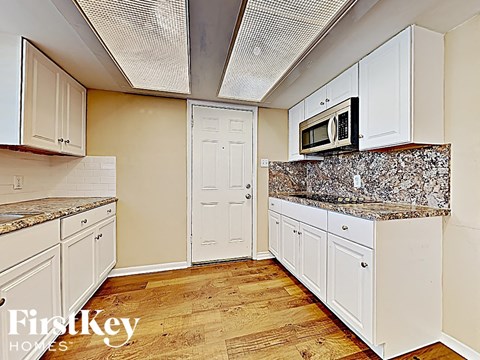 a kitchen with white cabinets and granite counter tops