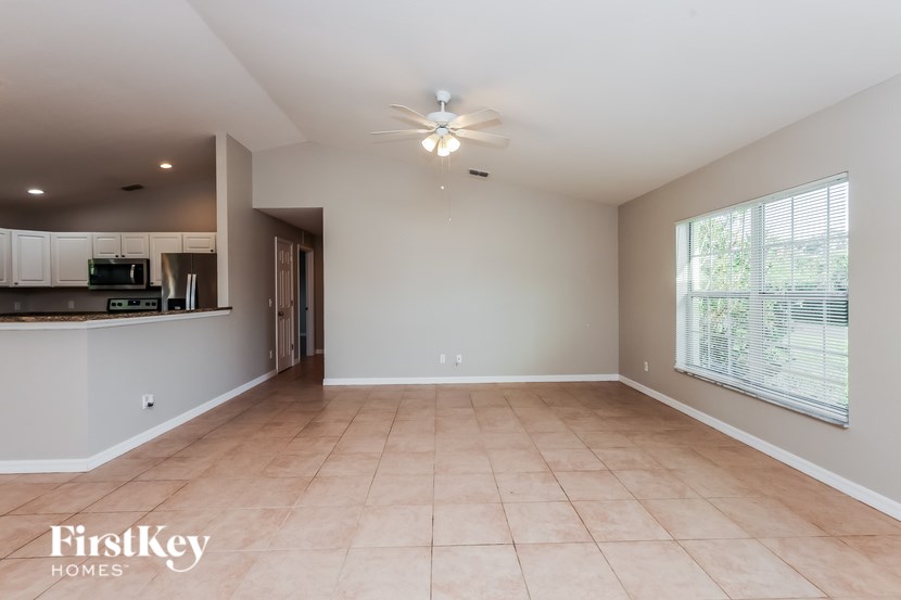 A spacious room with a ceiling fan and a window with blinds.