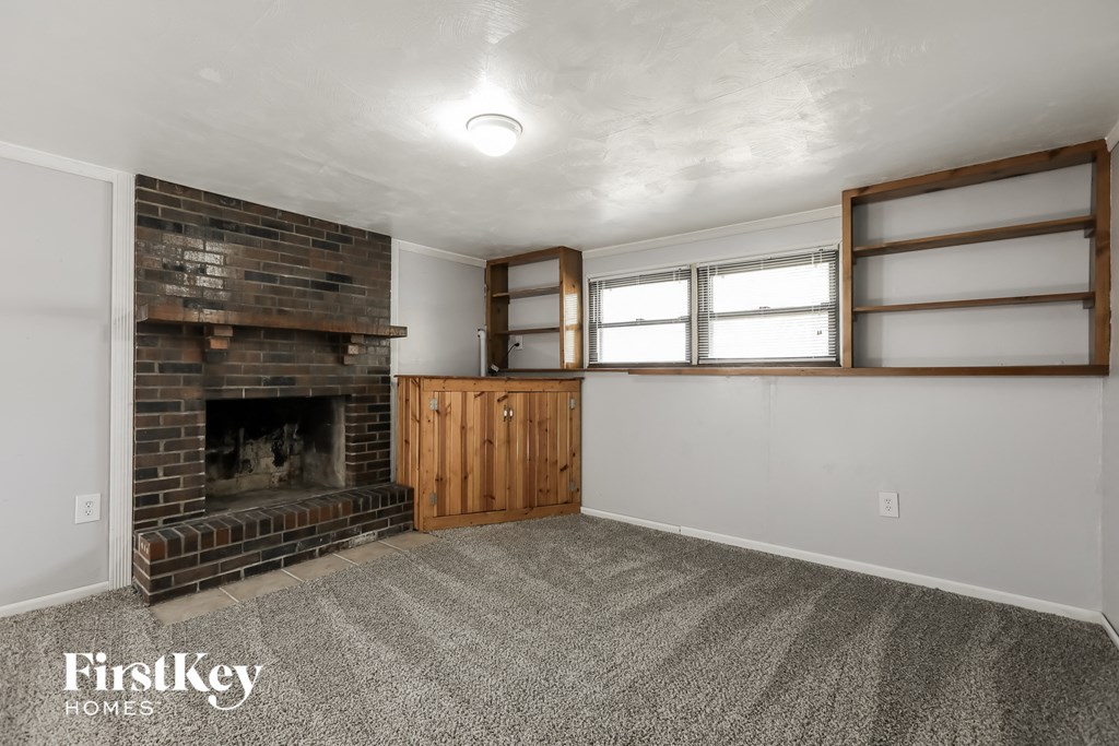 a living room with a brick fireplace and a window