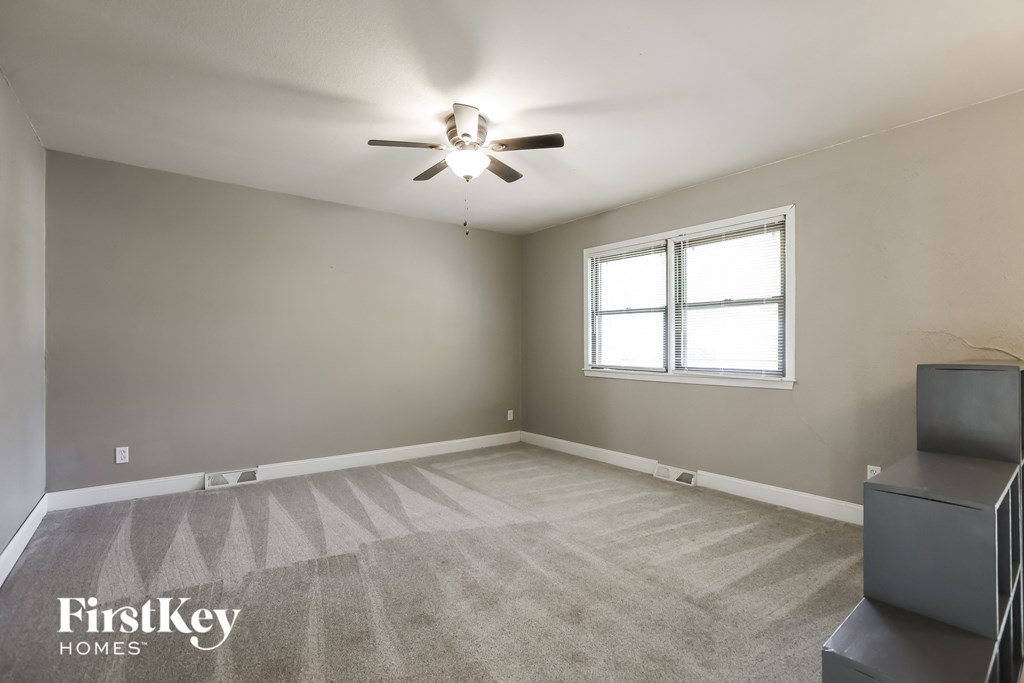 an empty living room with a ceiling fan and a window