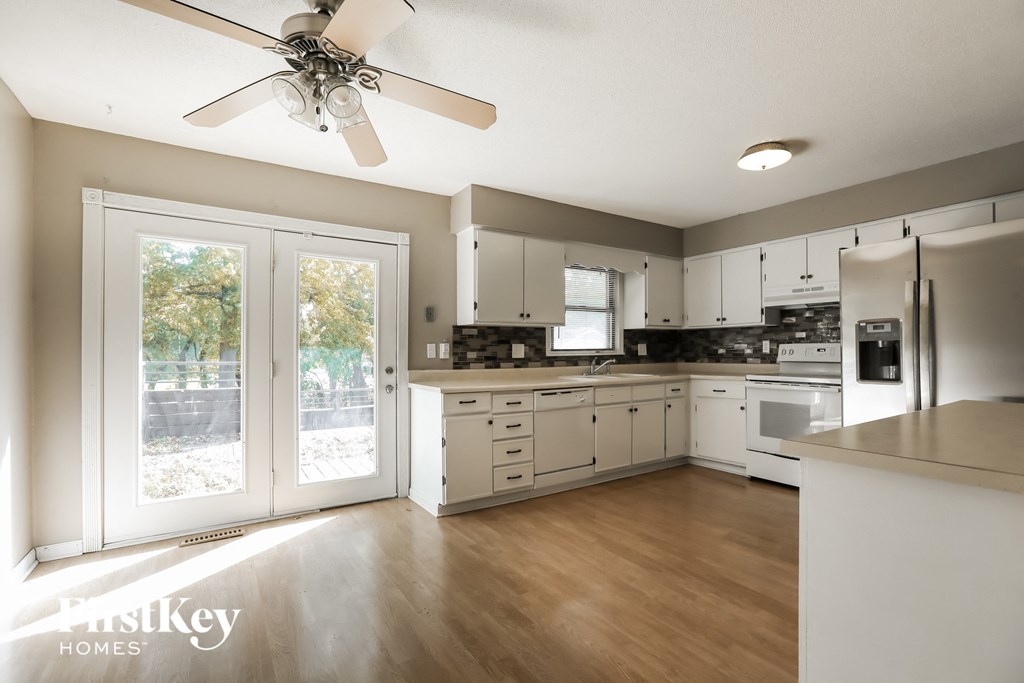 a large kitchen with white cabinets and a sliding glass door
