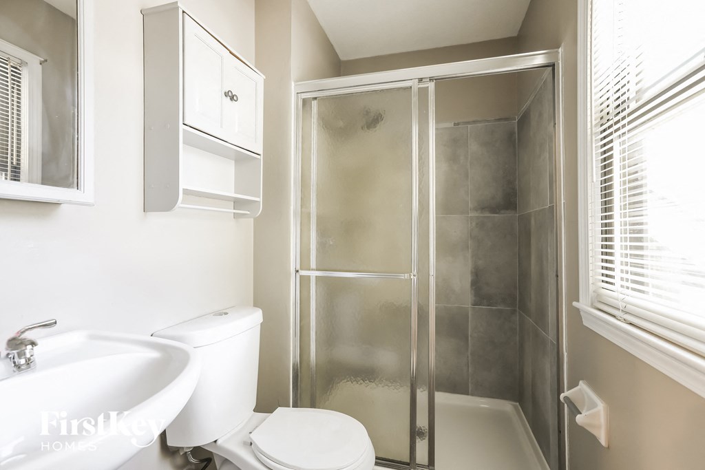 a white bathroom with a shower toilet and sink