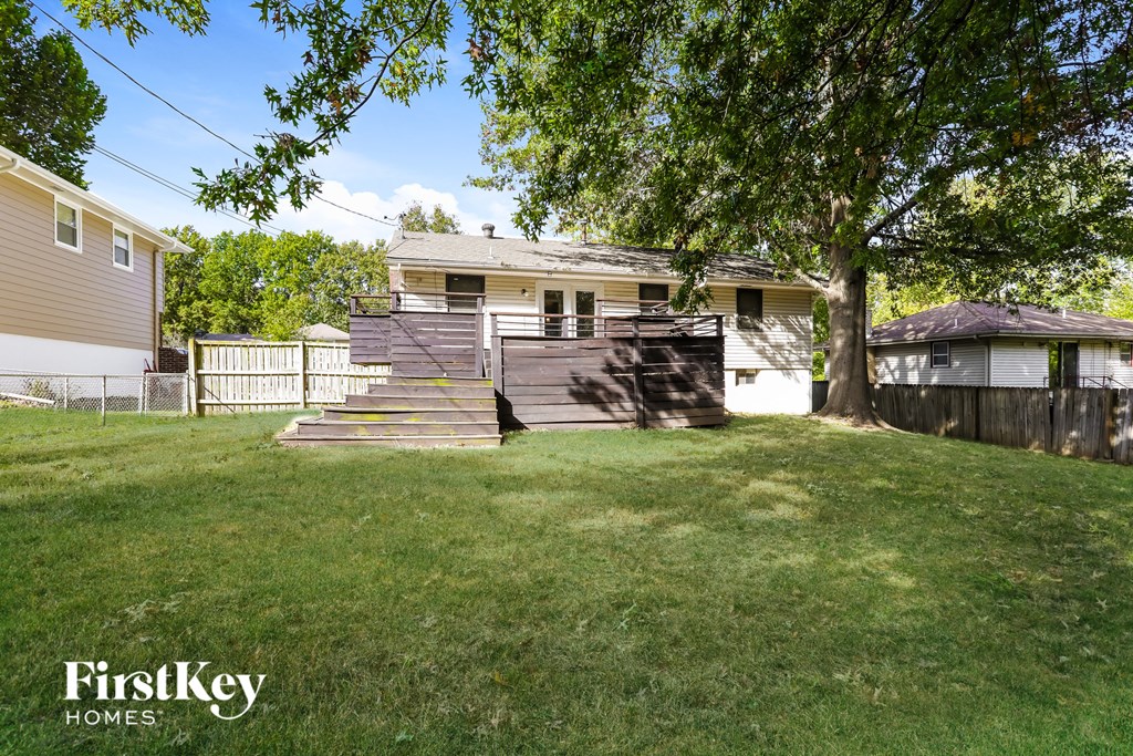 a backyard with a tree and stairs in front of a house