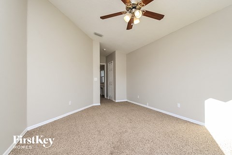 the spacious living room has a ceiling fan and beige carpet