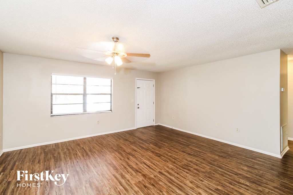 an empty living room with a ceiling fan and a window