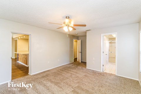 a spacious living room with a ceiling fan and a carpet