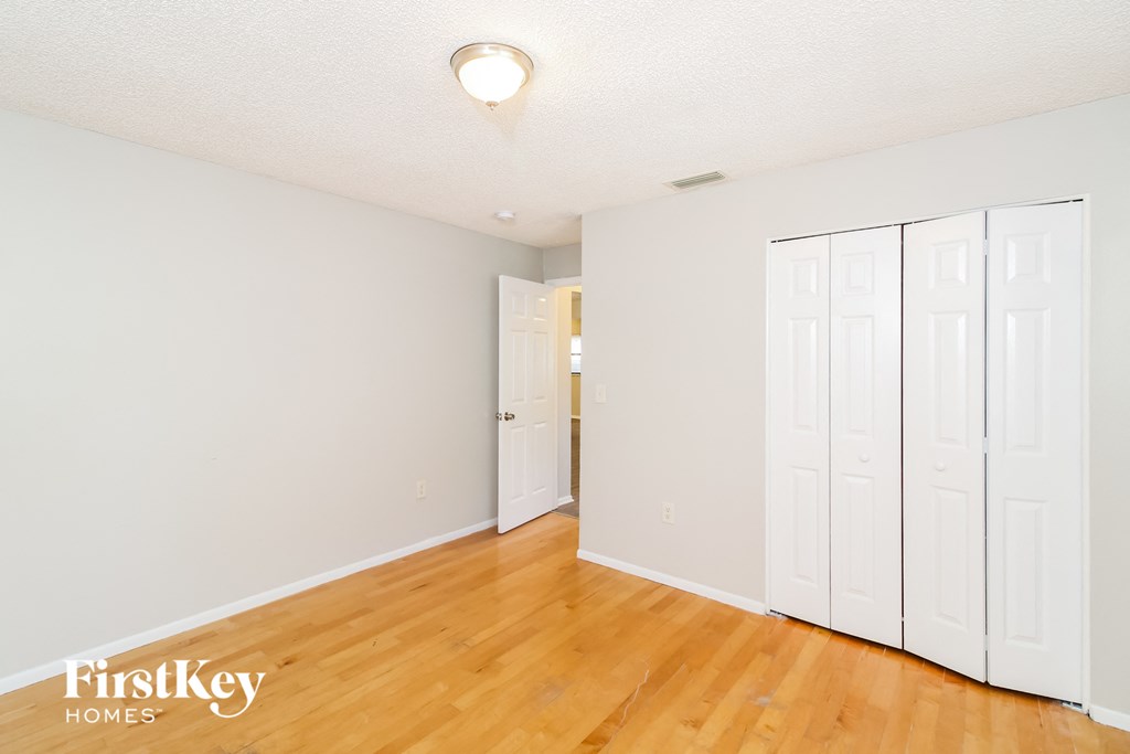 a bedroom with white walls and wood floors and white closets