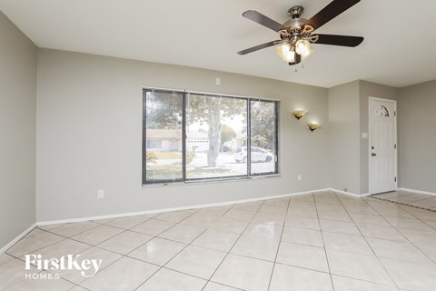 A spacious room with a ceiling fan and a large window.
