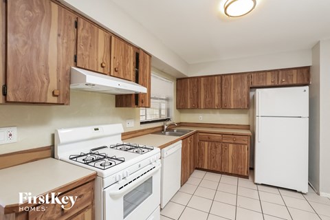 A kitchen with wooden cabinets and a white stove top oven.