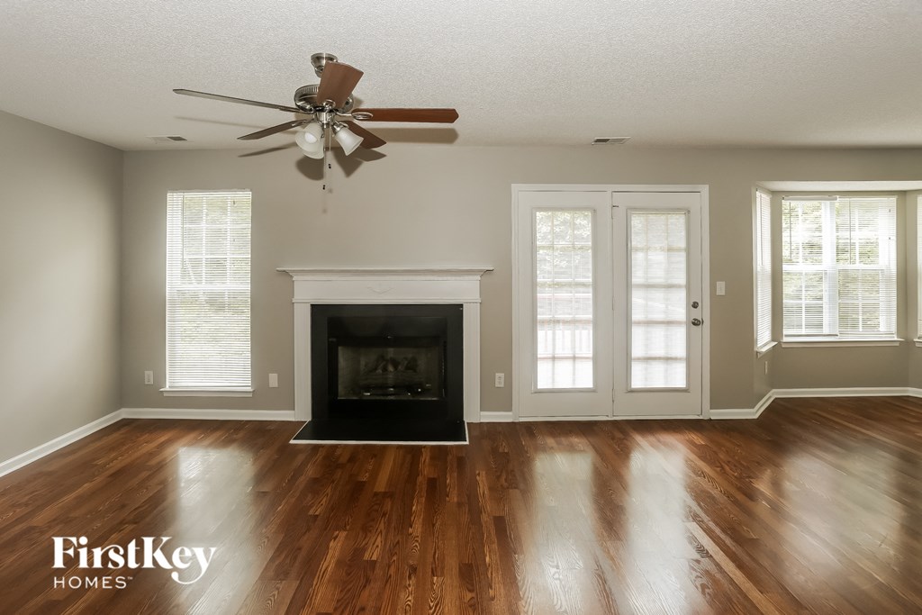 an empty living room with a fireplace and a ceiling fan