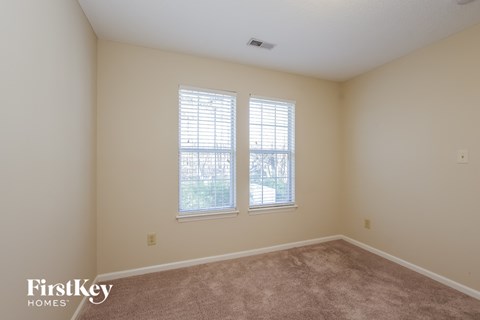 a bedroom with two windows and a carpeted floor
