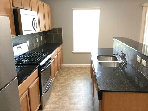 A kitchen with black countertops and wooden cabinets.