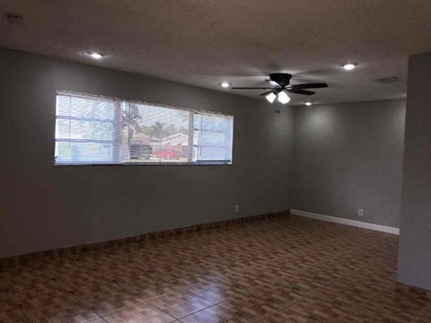 an empty living room with a ceiling fan and a window