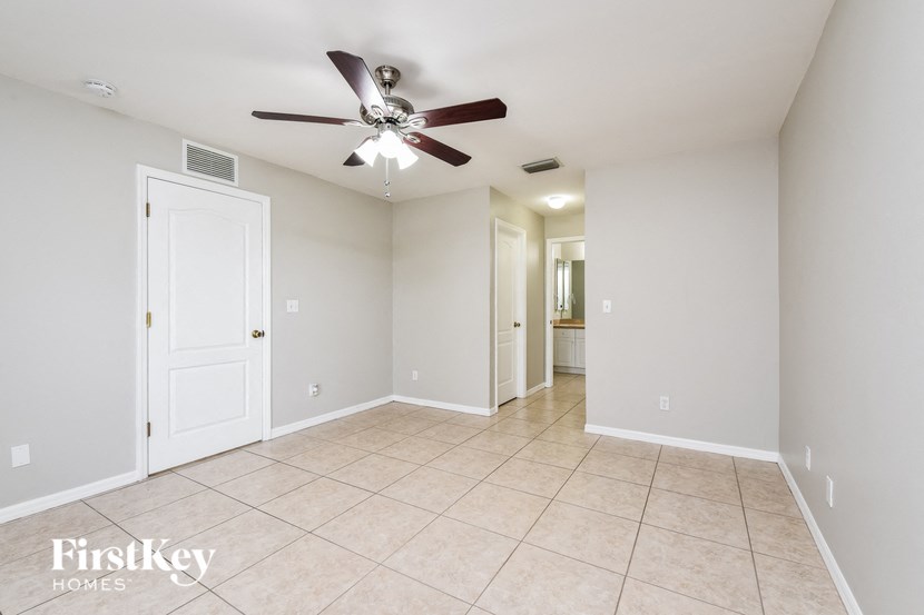 an empty living room with a ceiling fan and a tiled floor