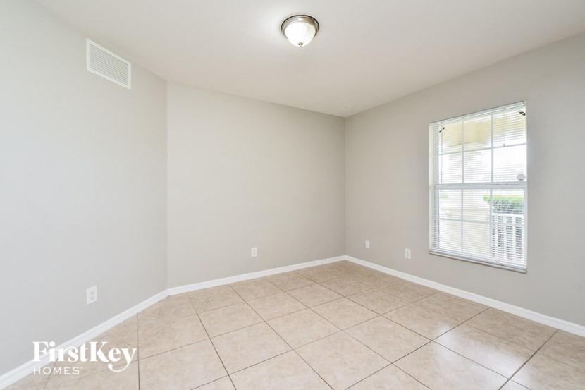 an empty living room with tiled floors and a window