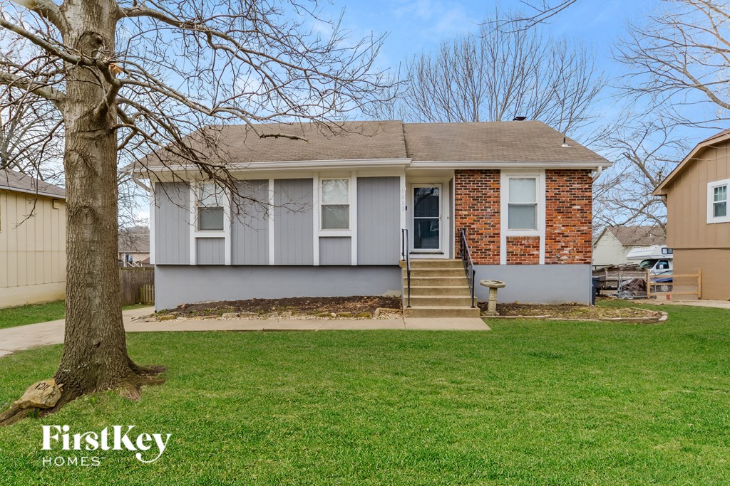 a small gray house with a yard and a tree