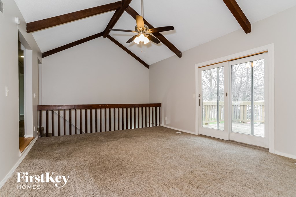 an empty living room with a ceiling fan and a window