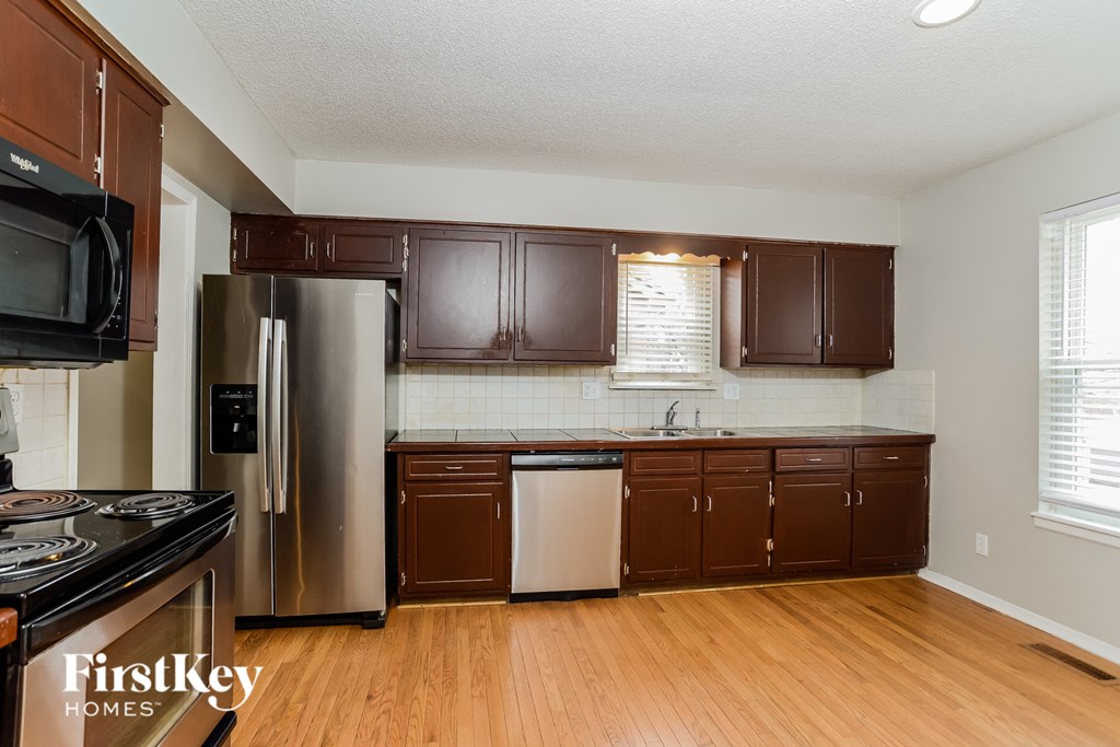 a kitchen with brown cabinets and a stainless steel refrigerator