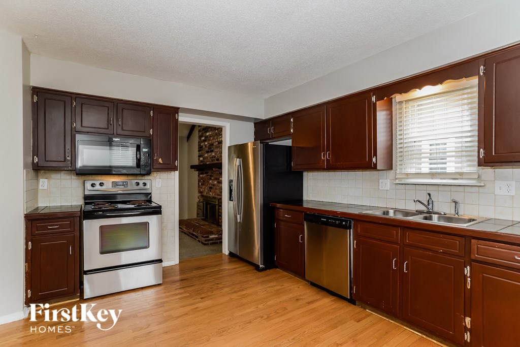 a kitchen with brown cabinets and white appliances and a wooden floor