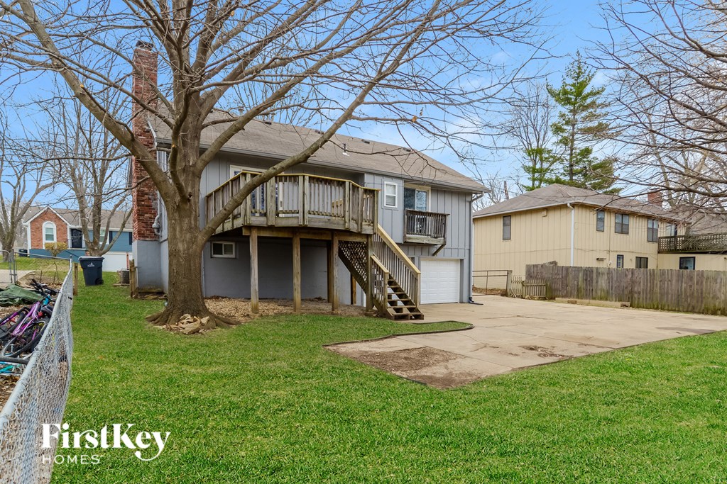 a home with a deck and a tree in the yard