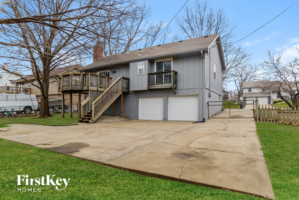 a gray house with a concrete driveway and a deck