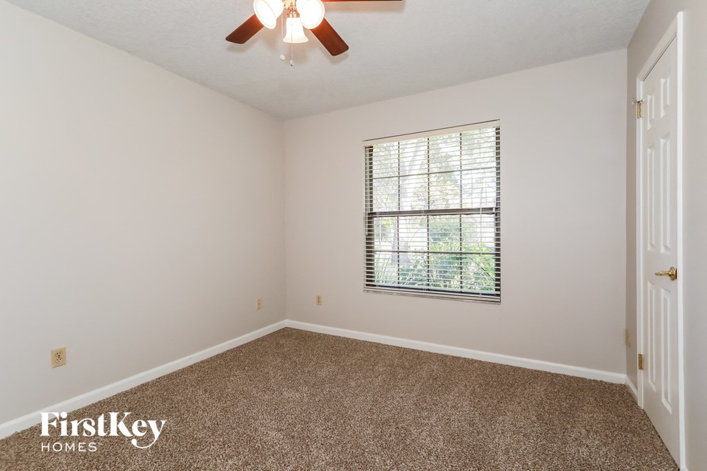 a bedroom with carpet and a window and a ceiling fan