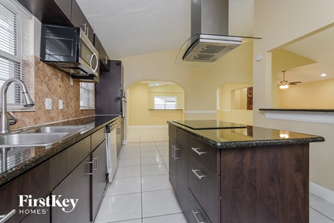 A kitchen with a black counter top and a stainless steel sink.