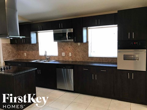 A kitchen with black cabinets and a stainless steel oven.