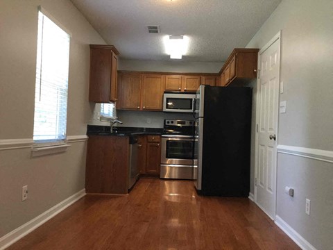 A kitchen with wooden cabinets and a black refrigerator.