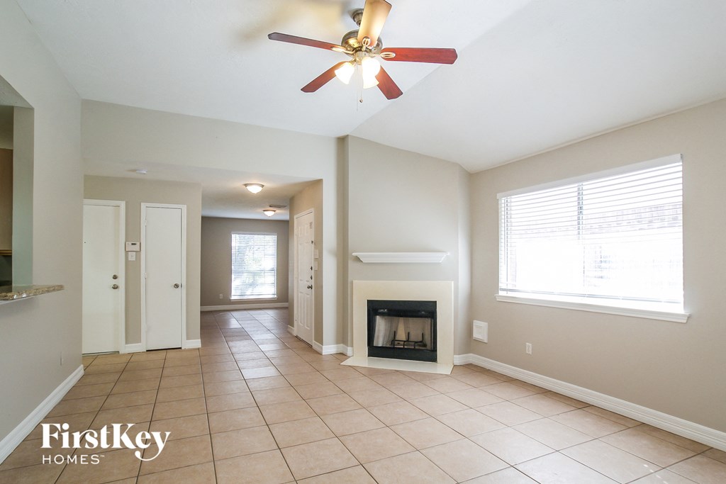 a living room with a fireplace and a ceiling fan