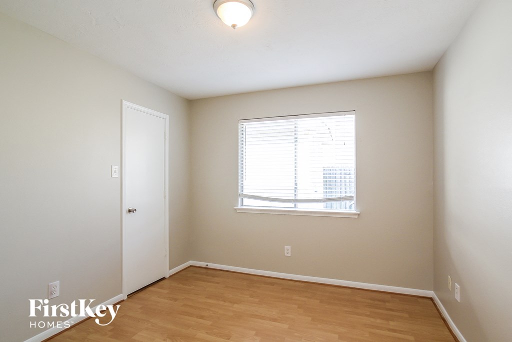 a bedroom with a wood floor and a window