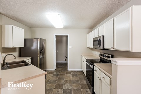 A kitchen with a refrigerator, sink, oven, and microwave.